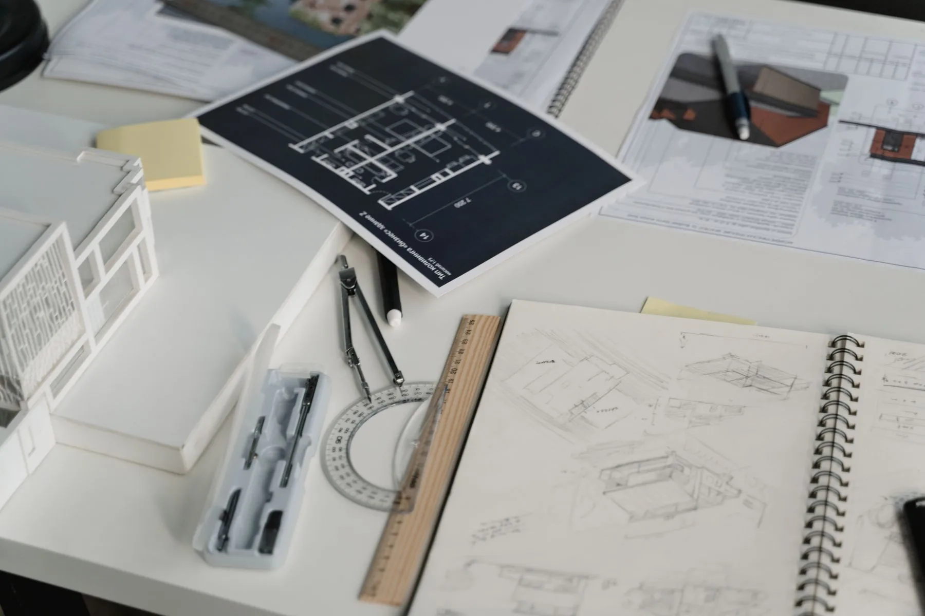 Construction drawings, a scale model, and drafting tools on a desk